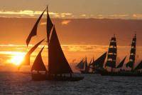 Корабли и яхты под парусами в море на закате солнца